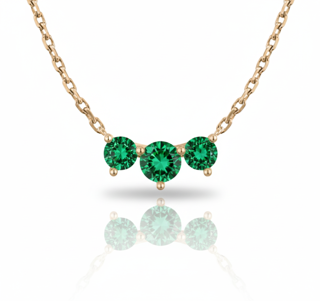 Rose gold necklace with three green gemstones on a white background