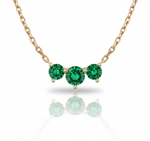 Rose gold necklace with three green gemstones on a white background