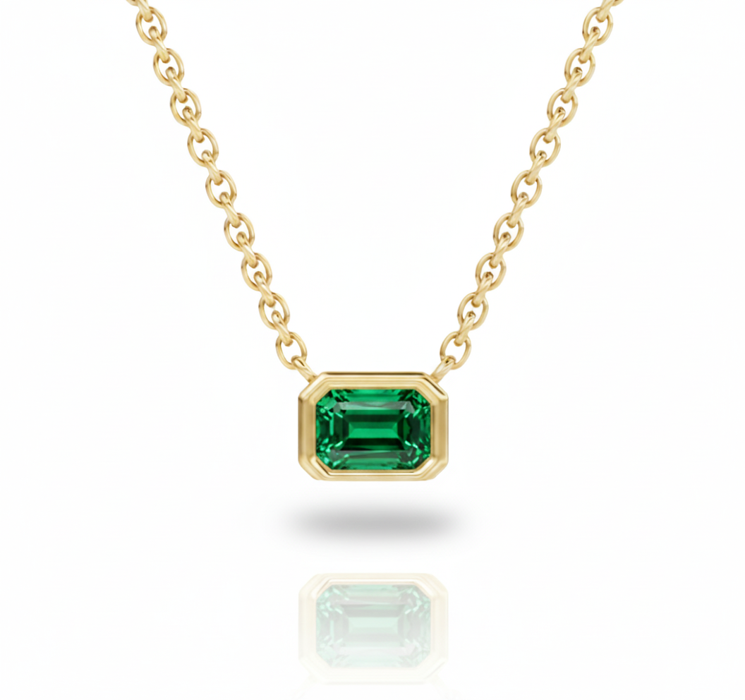 Gold necklace with a green gemstone on a white background