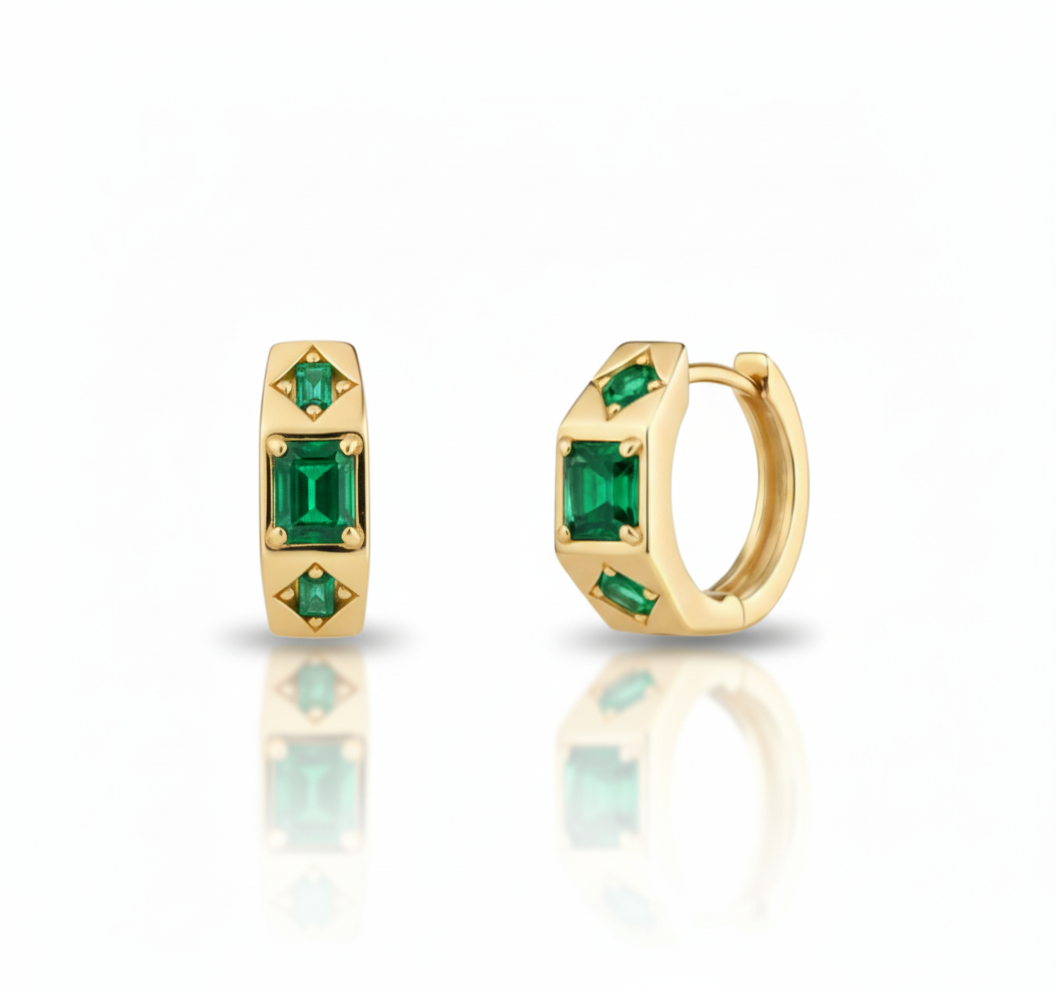 Gold hoop earrings with green gemstones on a white background