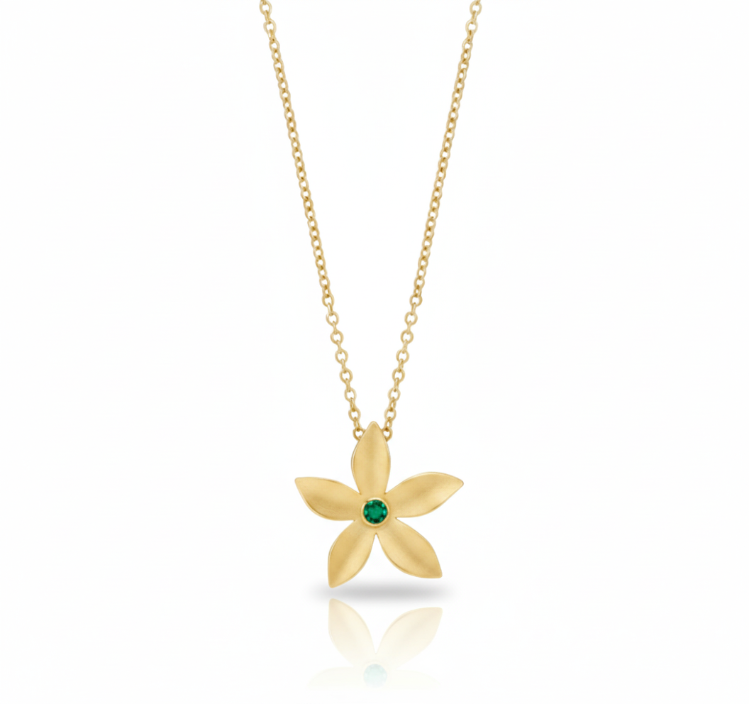 Gold flower-shaped necklace with a green gemstone on a white background