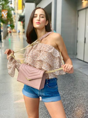 Woman holding a pink handbag on a city street