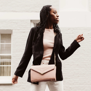 Woman holding a pink handbag against a white wall