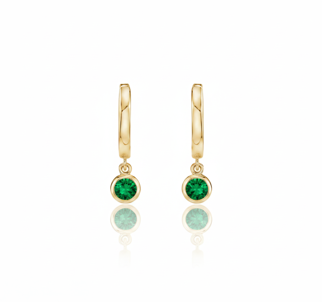 Gold hoop earrings with green gemstones on a white background