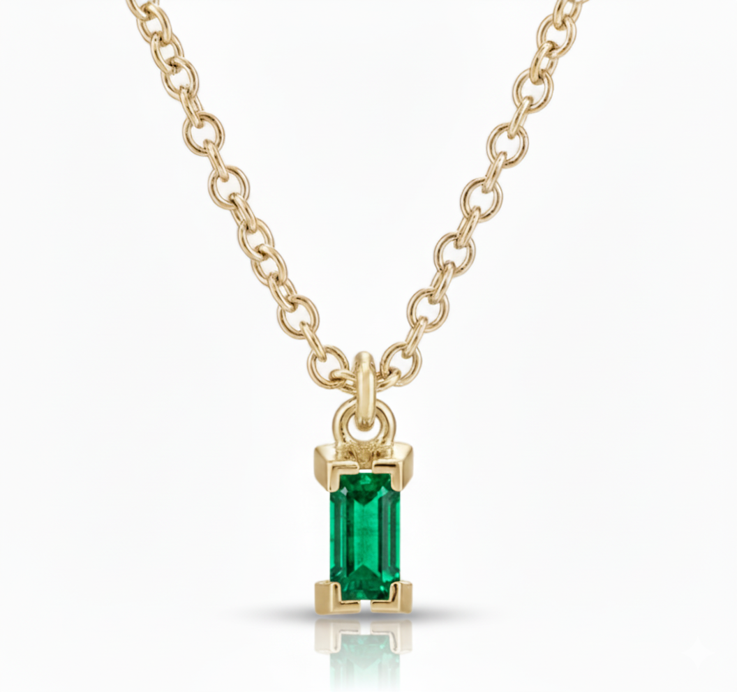 Gold necklace with a green gemstone pendant on a white background