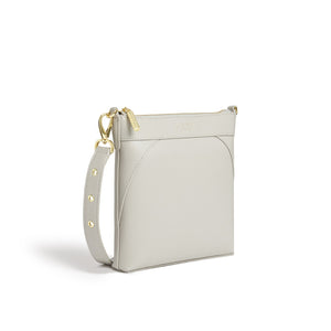 Light gray crossbody bag with gold accents on a white background
