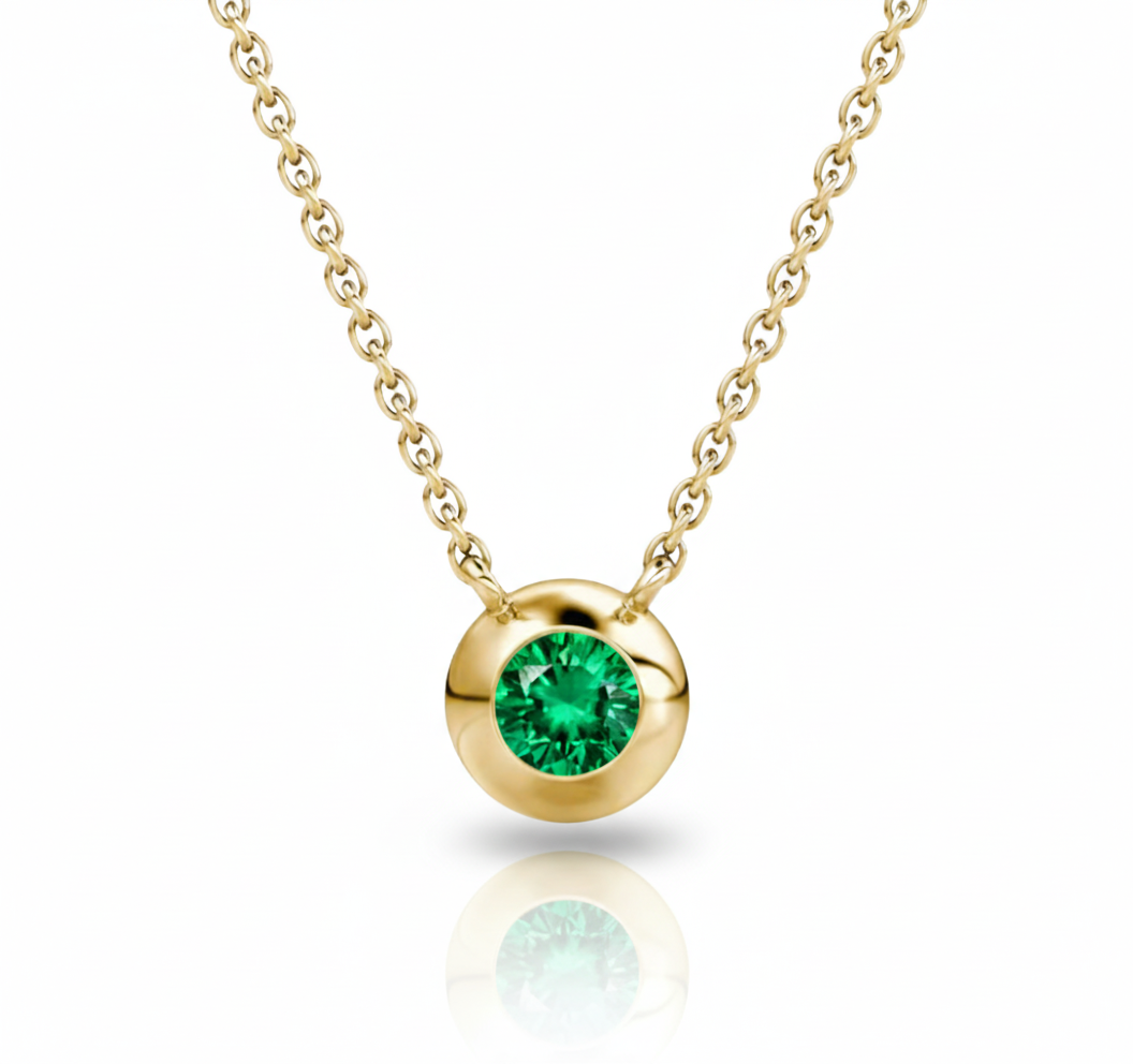 Gold necklace with a green gemstone pendant on a white background