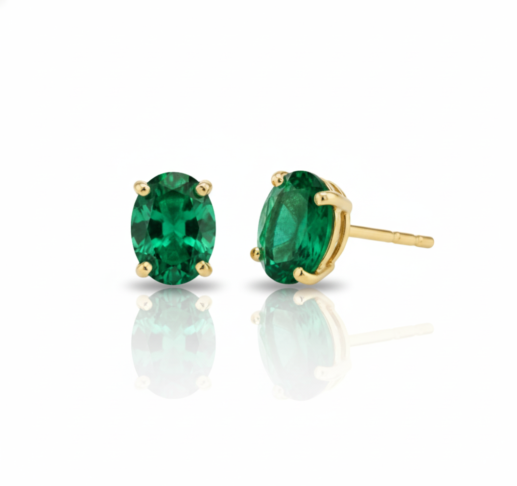 Pair of emerald green stud earrings with gold settings on a white background