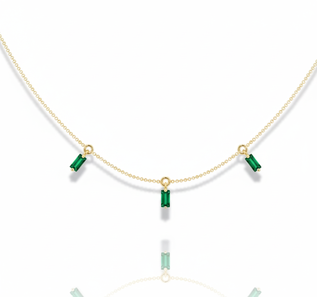 Gold necklace with green gemstones on a white background
