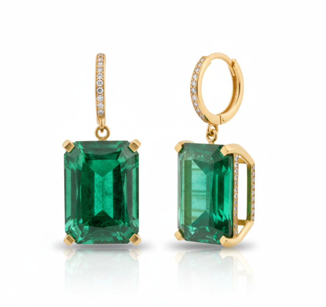 Gold earrings with emerald green gemstones on a white background