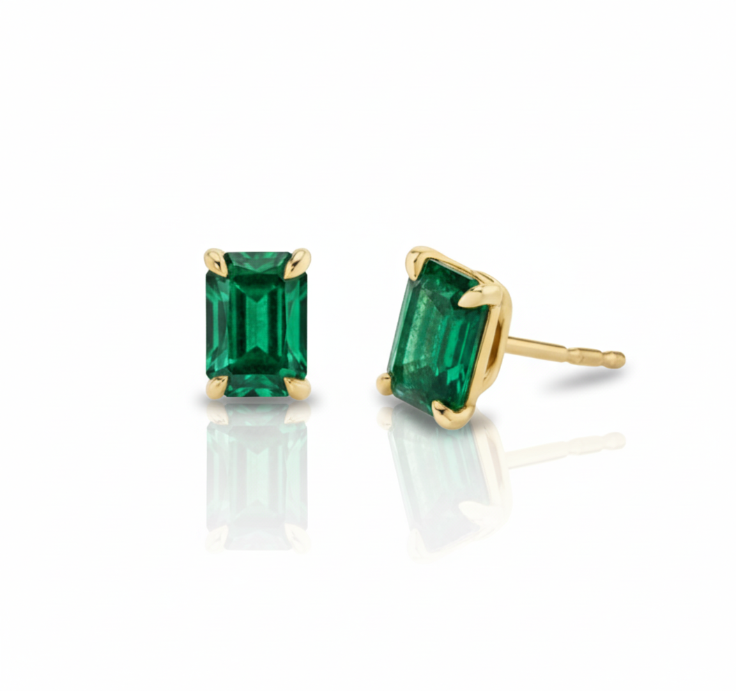 Gold earrings with green gemstones on a white background